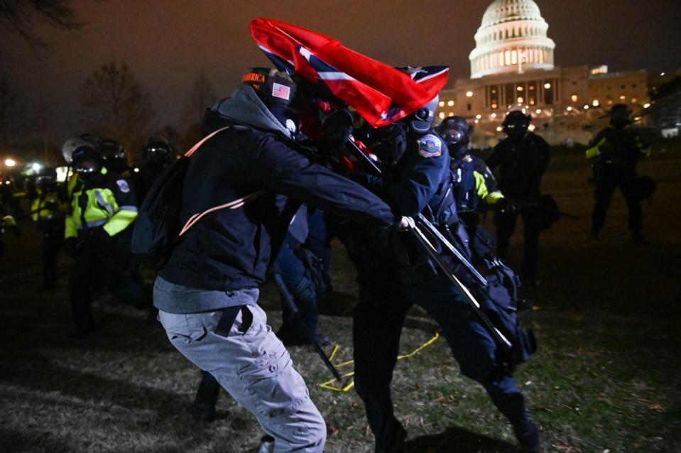 A supporter of US President Donald Trump struggles with a riot policeman after the protester pushed a line of police outside the Capitol building (AFP via Getty Images)