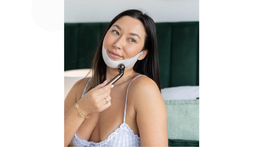 Woman using TruTone's Advanced Dermal Sculpting Mask and roller