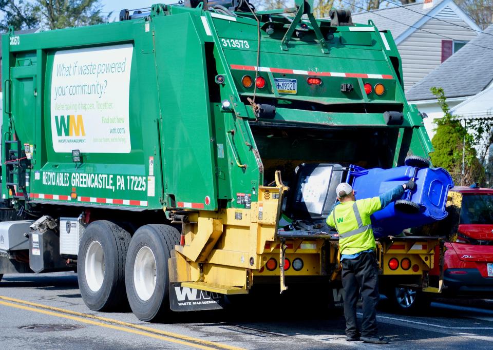 A Waste Management employee empties a recycling cart into one of the company's trucks along Avon Road on the morning of Monday, April 15, 2024. Recycling collection is a primary reason the city's new refuse collection contract has gone up.