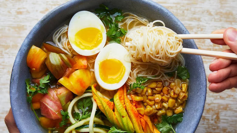 Chopsticks lifting ramen from bowl