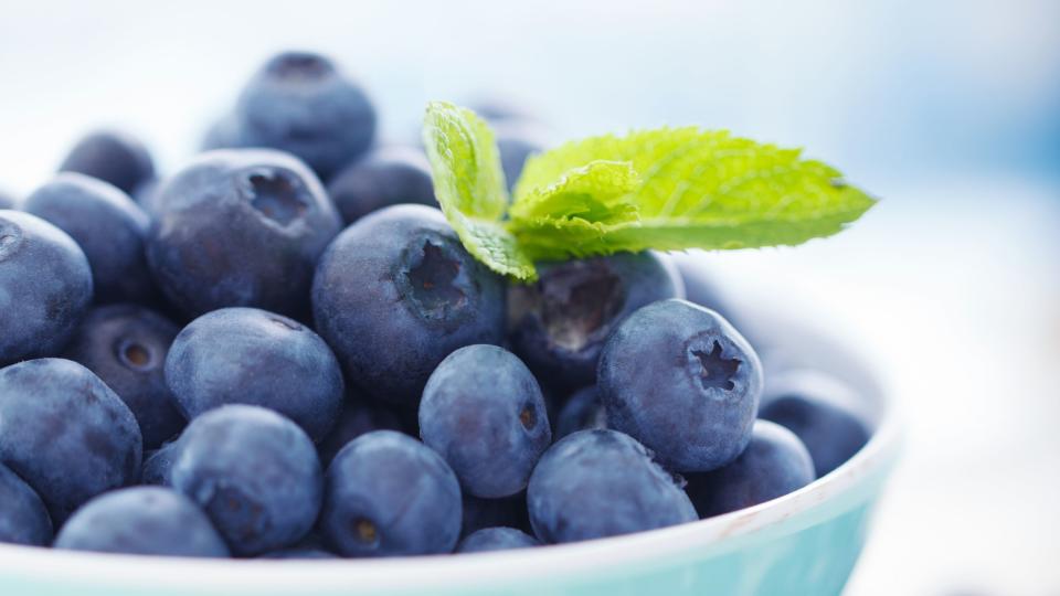 A blue bowl overfilled with blueberries