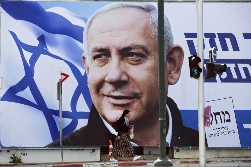 FILE - In this Thursday, March 28, 2019 file photo, a woman walks by an election campaign billboard showing Israeli Prime Minister Benjamin Netanyahu in Tel Aviv, Israel. In a charged campaign that has been heavy on insults and short on substance, Israel's conflict with the Palestinians has been notably absent from the discourse. (AP Photo/Oded Balilty, File)