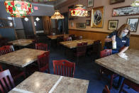 A table marked with a tape "X" that will remain unused, is next to Sara Kennely as she cleans one of the dining tables at Max's Allegheny Tavern, Thursday, June 4, 2020. The taped tables will be restricted to maintain social distancing when patrons are permitted to dine inside when most of southwest Pennsylvania loosens COVID-19 restrictions on Friday. (AP Photo/Keith Srakocic)