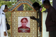 In this Oct. 21, 2018, photo, Sister Laurentina, left, stands next to the tombstone of Adelina Sau in Abi village in West Timor, Indonesia. Adelina died while working as a maid for a Malaysian family. (AP Photo/Tatan Syuflana)