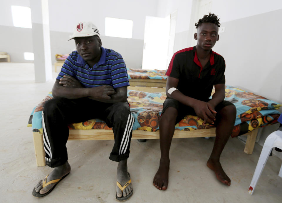 An unidentified Malian survivor, right, of a shipwreck sits in the Red Crescent center of Zarzis, southern Tunisia, Thursday, July 4, 2019. The U.N. migration agency says a boat carryinsg 86 migrants from Libya sank in the Mediterranean overnight, and just three people on board survived, with 82 missing. The shipwreck late Wednesday off the Tunisian city of Zarzis came a day after a deadly airstrike on a Libyan detention center that killed at least 44 migrants. (AP Photo/Sami Jelassi)