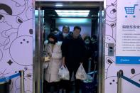 Customers wearing masks stand in an elevator after shopping at Alibaba's Hema Fresh chain store, following the coronavirus outbreak, in Beijing