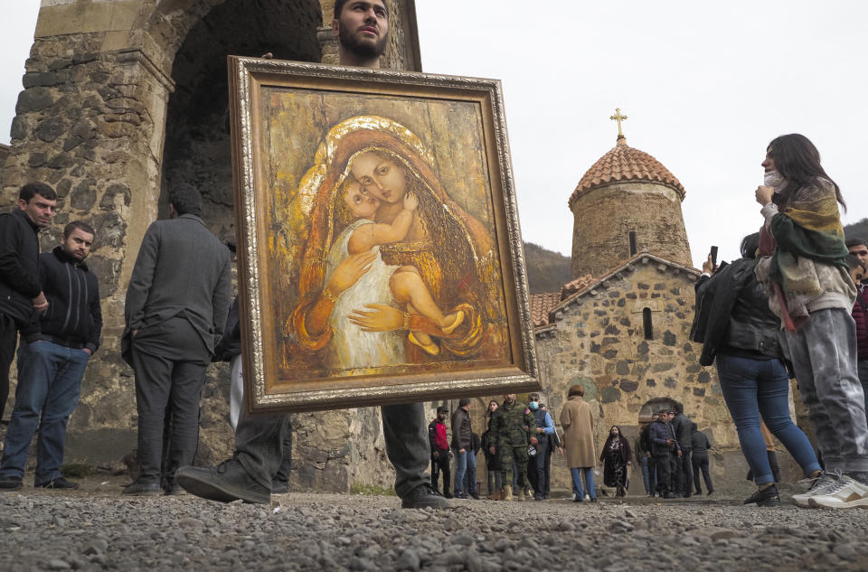 A man holds an icon from the Dadivank, an Armenian Apostolic Church monastery dating to the 9th century, as ethnic Armenians leave the separatist region of Nagorno-Karabakh to Armenia, Saturday, Nov. 14, 2020. The territory is to be turned over to Azerbaijan on Sunday as part of territorial concessions in an agreement to end six weeks of intense fighting with Armenian forces. (AP Photo/Dmitry Lovetsky)