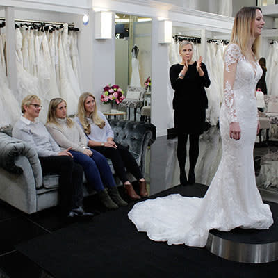 a woman trying on a wedding dress in front of her family and friends