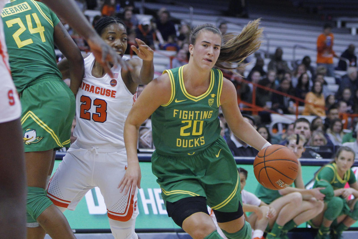 Oregon's Sabrina Ionescu, right, dribbles past Syracuse's Kiara Lewis, left, in the first quarter of an NCAA college basketball game in Syracuse, N.Y., Sunday, Nov. 24, 2019. (AP Photo/Nick Lisi)