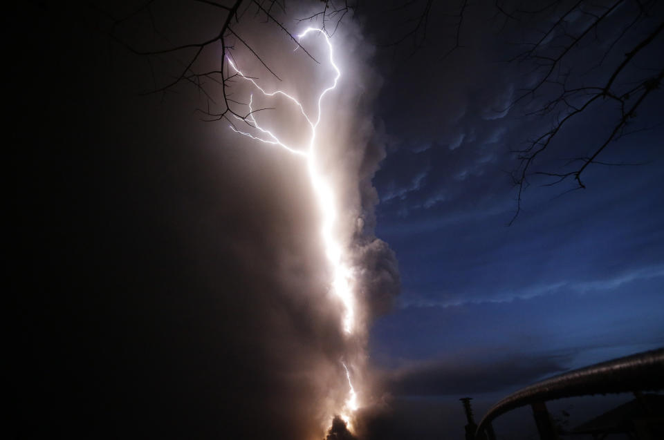 Lightning flashes as Taal Volcano erupts Sunday Jan. 12, 2020, in Tagaytay, Cavite province, outside Manila, Philippines. A tiny volcano near the Philippine capital that draws many tourists for its picturesque setting in a lake belched steam, ash and rocks in a huge plume Sunday, prompting thousands of residents to flee and officials to temporarily suspend flights. (AP Photo/Aaron Favila)