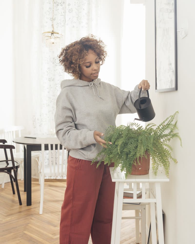 A woman watering a plant in her home