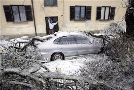 A power company worker removes broken wires next to an ice-covered car in Pivka February 4, 2014. REUTERS/Srdjan Zivulovic