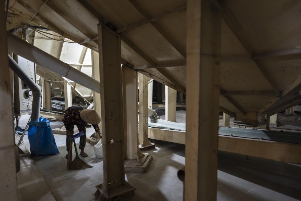 A worker sweeps the floor beneath rice processors in a warehouse at Hoang Minh Nhat, a rice export company in Can Tho, Vietnam, Friday, Jan. 26, 2024. The Mekong Delta, where 90% of Vietnam's exported rice is farmed, is one of the world's regions most vulnerable to climate change. (AP Photo/Jae C. Hong)