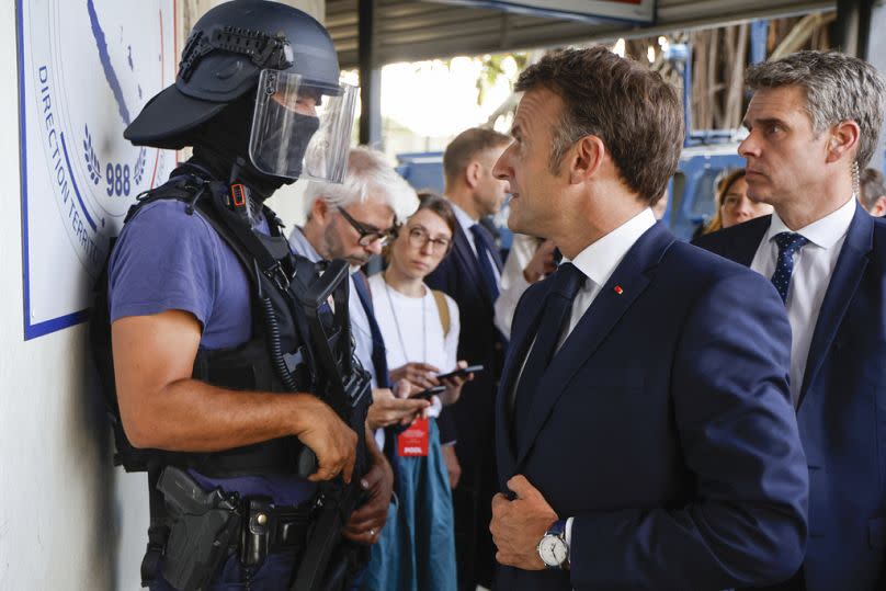 French President Emmanuel Macron talks to a policeman upon his arrival at the central police station in Noumea, New Caledonia, Thursday, May 23, 2024.