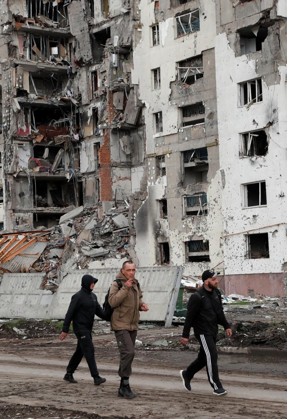 People walk along a street near a destroyed residential building in Mariupol (Reuters)