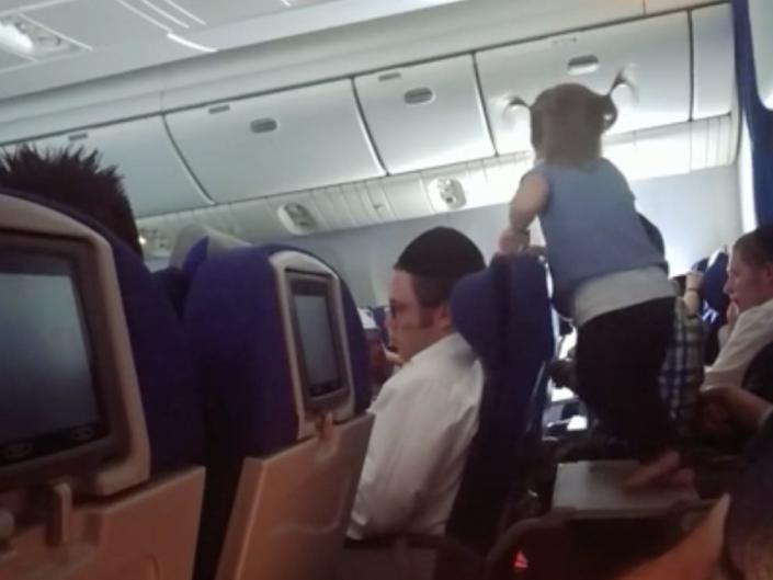 Small child standing on top of tray table on an airplane