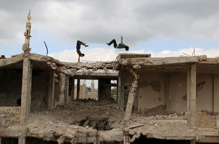 Parkour coach Ibrahim al-Kadiri (R), 19, and Muhannad al-Kadiri, 18, demonstrate their Parkour skills amid damaged buildings in the rebel-held city of Inkhil, west of Deraa, Syria, April 7, 2017. Ibrahim discovered Parkour in Jordan, where he had fled to escape the war. Back in his home town since 2015, he now leads a group of 15 practitioners. REUTERS/Alaa Al-Faqir