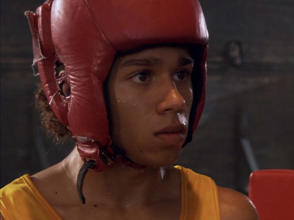 Corbin Bleu in Jump In seating a yellow tank top and boxing helmet