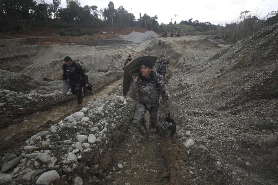 National Police officers walk at an illegal gold mining operation as they work to destroy it as part of the Armed Forces' "Operation Guamuez III" in Magui Payan, Colombia, Tuesday, April 20, 2021. Illegal gold mining is common in Colombia, especially wildcat mines in poverty-stricken areas dominated by criminal gangs with little state presence. (AP Photo/Fernando Vergara)