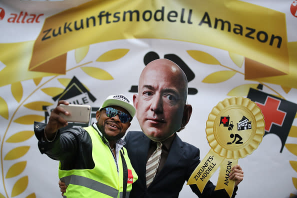 An Amazon warehouse worker shoots a selfie with an activist dressed as Amazon CEO Jeff Bezos during a protest gathering outside the Axel Springer building on April 24, 2018 in Berlin. Several hundred Amazon warehouse workers from Germany, Poland and Italy protested outside the Axel Springer building, where inside Bezos was scheduled to receive an award for innovation. The workers claim Amazon pays too little and offers too few benefits. (Photo by Sean Gallup/Getty Images)