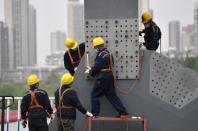 Workers wearing protective masks work on a bridge after the construction works resumed, in Wuhan