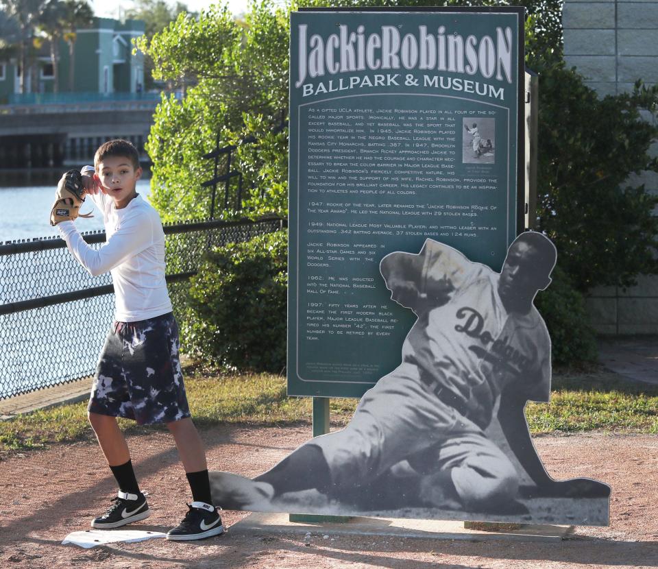 A young baseball fan takes a batters stance next to one of the many tributes to Jackie Robinson at the ballpark named after him, Friday April 12, 2024 as the youngster arrives with family for a game between the Daytona Tortugas and Palm Beach Cardinals.