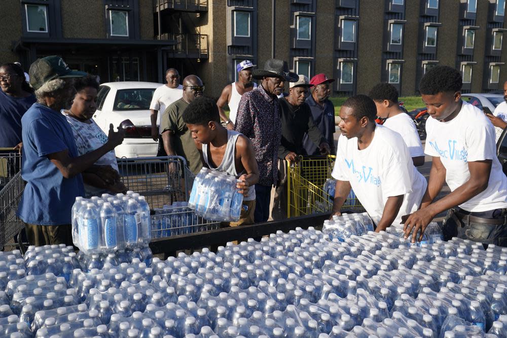 Residents of the Golden Keys Senior Living apartments flock to a trailer full of water being delivered by the AIDS Healthcare Foundation in Jackson, Miss., on Sept. 1, 2022. (AP Photo/Steve Helber, File)