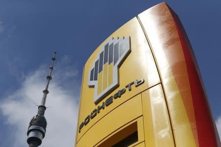 The logo of Russia's top crude producer Rosneft is seen on a price information board of a gasoline station, with the Ostankino television and radio tower seen in the background, in Moscow July 17, 2014. REUTERS/Sergei Karpukhin