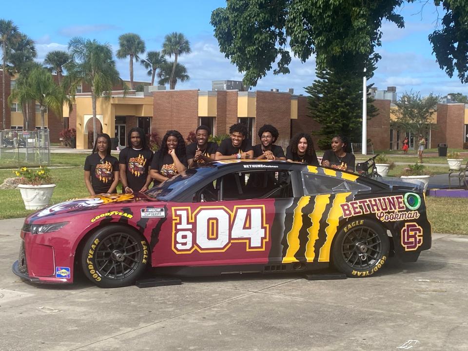 Bethune-Cookman University students involved with the NASCAR Campus Lab program pose behind a specially wrapped race car that was displayed on the Daytona Beach campus on Oct. 27.