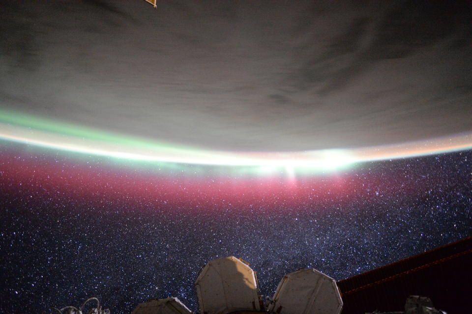 upside-down earth with pink auroras flowing from the surface. at the bottom is space with stars, and part of a space station