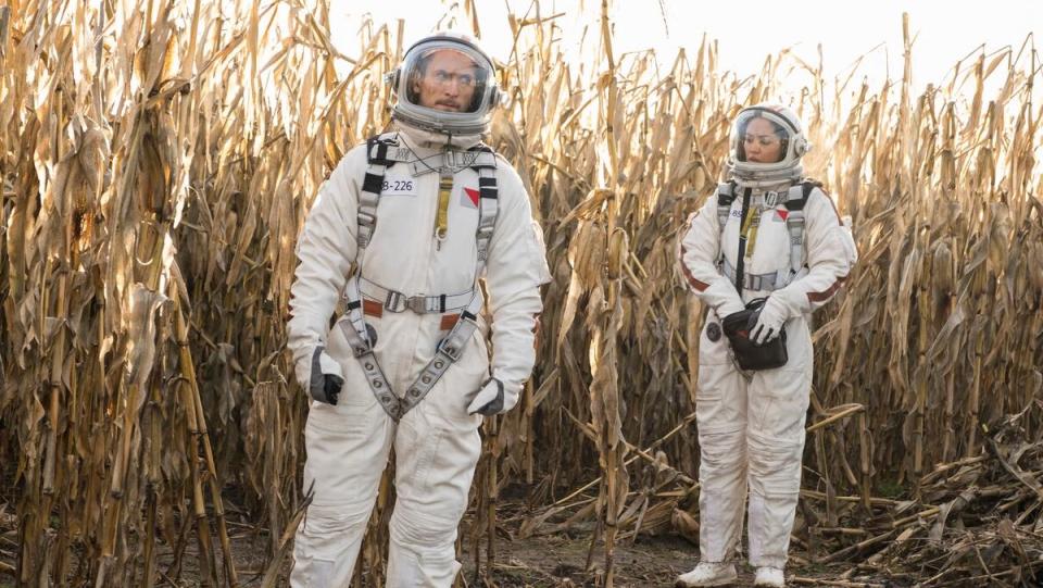 Bryan and Finola in spacesuits standing in a wheat field on Debris