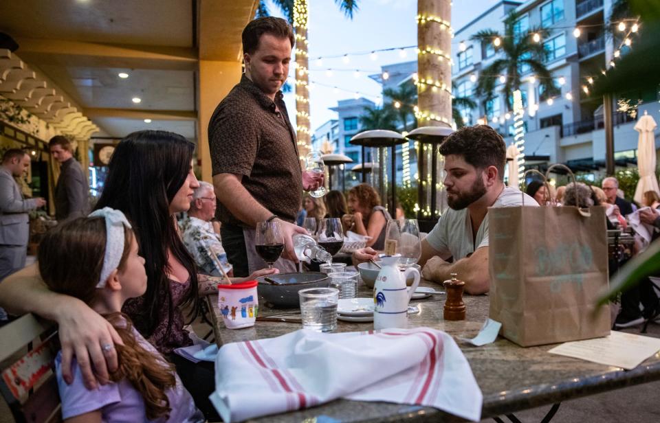 Nathan Cole, a server at Bar Tulia in Mercato, tends to his table with patrons Gala Hejni, Josh Luizzi and their daughter Lianna visiting the restaurant Saturday evening, January 27, 2024.