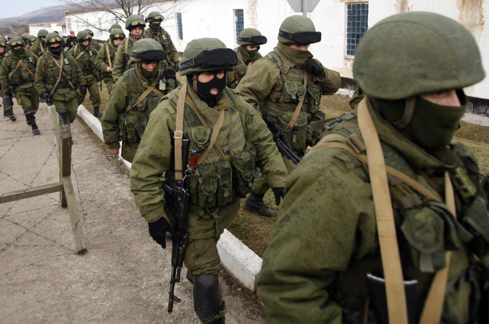 Unidentified armed men patrol around a Ukraine's infantry base in Perevalne, Ukraine, Sunday, March 2, 2014. Hundreds of armed men in trucks and armored vehicles surrounded the Ukrainian military base Sunday in Crimea, blocking its soldiers from leaving. The outnumbered Ukrainians placed a tank at the base's gate, leaving the two sides in a tense standoff. (AP Photo/Darko Vojinovic)