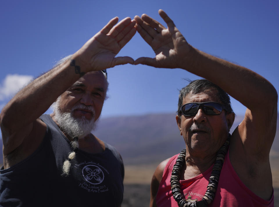 Elders Billy Keliiokalani Freitas, left, and Kini Palmyra Kaleilani in Mauna Kea, Hawaii on Saturday, July 15, 2023 put their hands together creating a symbol of support and solidarity for protecting Mauna Kea and for those blocking construction of a new telescope on the mountain. The symbol was birthed out of protests over the planned Thirty Meter Telescope. Freitas was one of the elders arrested during the 2019 protests. (AP Photo/Jessie Wardarski)