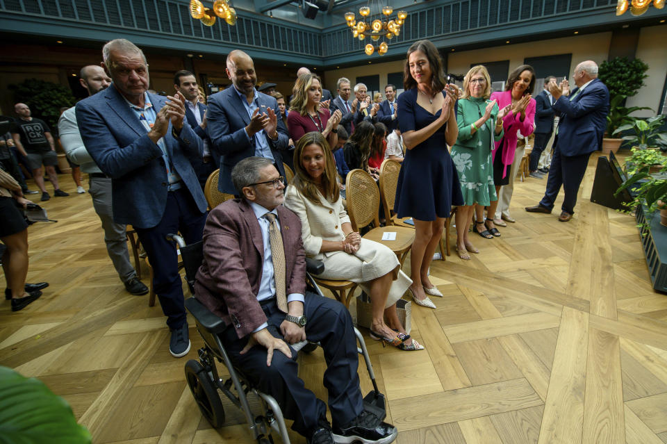 Dan and Jennifer Gilbert, left, are given a standing ovation during a press conference at the Book Tower in Detroit, Wednesday, Sept. 6, 2023, to announce a nearly $375 million philanthropic effort to fight strokes and research cures for neurofibromatosis. (David Guralnick/Detroit News via AP)