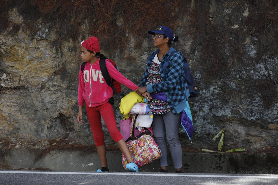 In this Sept. 1, 2018 photo, Venezuelan Sandra Cadiz holds the hand of her 10-year-old daughter, who's scared of the trucks racing by, as they wait for an opportunity to cross a highway on their way to the Berlin paramo, which leads to the city of Bucaramanga, Colombia, on their journey to Peru. Of the millions of Venezuelans who have fled their nation's spiraling hyperinflation, deadly medical shortages and withering democracy in an exodus that rivals even the European refugee crisis in numbers, they were the least fortunate: The ones who could not afford the comfort of a bus or plane. (AP Photo/Ariana Cubillos)