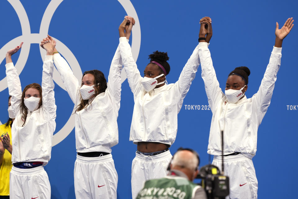 United States women's 4x100m freestyle relay team wave as they stand on the podium to receive their bronze medals at the 2020 Summer Olympics, Sunday, July 25, 2021, in Tokyo, Japan. (AP Photo/Martin Meissner)