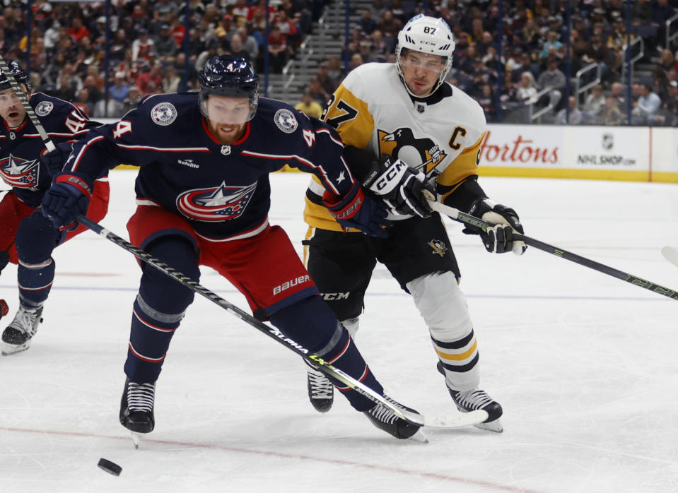 Columbus Blue Jackets defenseman Vladislav Gavrikov, left, works against Pittsburgh Penguins forward Sidney Crosby during the first period of an NHL hockey game in Columbus, Ohio, Saturday, Oct. 22, 2022. (AP Photo/Paul Vernon)