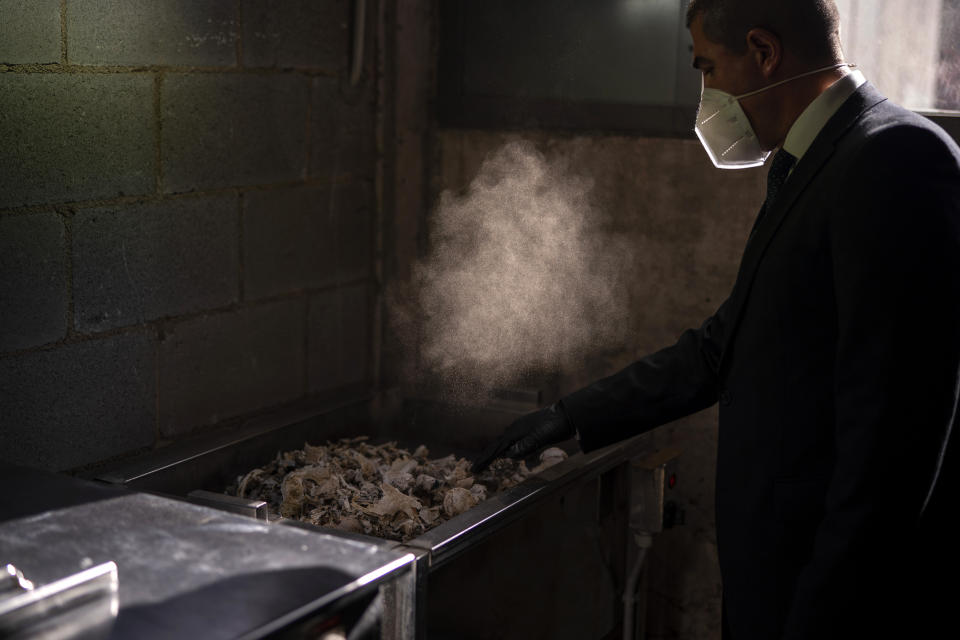 A mortuary worker collects the ashes of a COVID-19 victim from an oven after the remains where cremated at Mémora mortuary in Girona, Spain, Thursday, Nov. 19, 2020. (AP Photo/Emilio Morenatti)