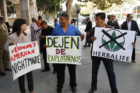 Demonstrators protesting against Herbalife, a nutrition and supplements company, hold signs outside the Ronald Reagan State Office building in Los Angeles, California October 18, 2013. REUTERS/Fred Prouser