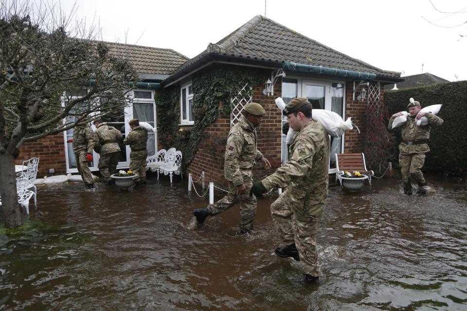 British army soldiers place sandbags at the entrance to a flooded house at Chertsey, England, Wednesday, Feb. 12, 2014. The River Thames has burst its banks after reaching its highest level for many years, flooding riverside towns upstream of London, including Chertsey which is about 30 miles west of central London. Some hundreds of troops have been deployed to assist with flood protection and to get medical assistance to the sick and vulnerable.(AP Photo/Sang Tan)