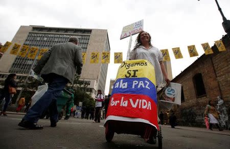 Una vendedora callejera camina bajo una pancarta en apoyo al plebiscito en Colombia en el centro de Bogotá, Colombia, el 29 de septiembre de 2016. Los colombianos comenzaron a votar el domingo en un plebiscito que decidirá si el país respalda un acuerdo de paz para que la guerrilla de las FARC deje las armas y se convierta en un partido político, o si prolongan el conflicto de 52 años. REUTERS/John Vizcaino/Files