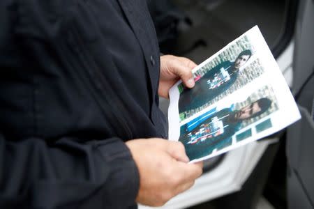 A German policeman holds the picture of a terrorist-subject infront of the main terminal of Berlin-Schoenefeld airport, in Schoenefeld, near Berlin, October 9, 2016, following a suspicion that a bomb attack was being planned in Germany. REUTERS/Axel Schmidt