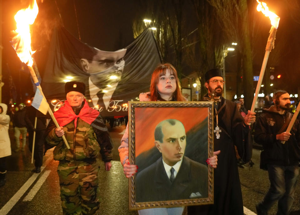 Activists of various nationalist parties carry torches and a portrait of Stepan Bandera during a rally in Kyiv, Ukraine, Saturday, Jan. 1, 2022. The rally was organized to mark the birth anniversary of Stepan Bandera, founder of a rebel army that fought against the Soviet regime and who was assassinated in Germany in 1959. (AP Photo/Efrem Lukatsky)