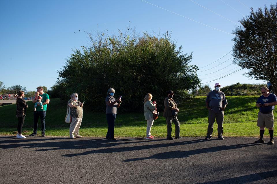 Voters who are among the last to vote for the day wear masks and social distance as they wait in a long line to cast their ballots on the first day of early voting for the presidential, state and local elections at the Maury County Election Commission in Columbia, Tenn., on Wednesday, Oct. 14, 2020.