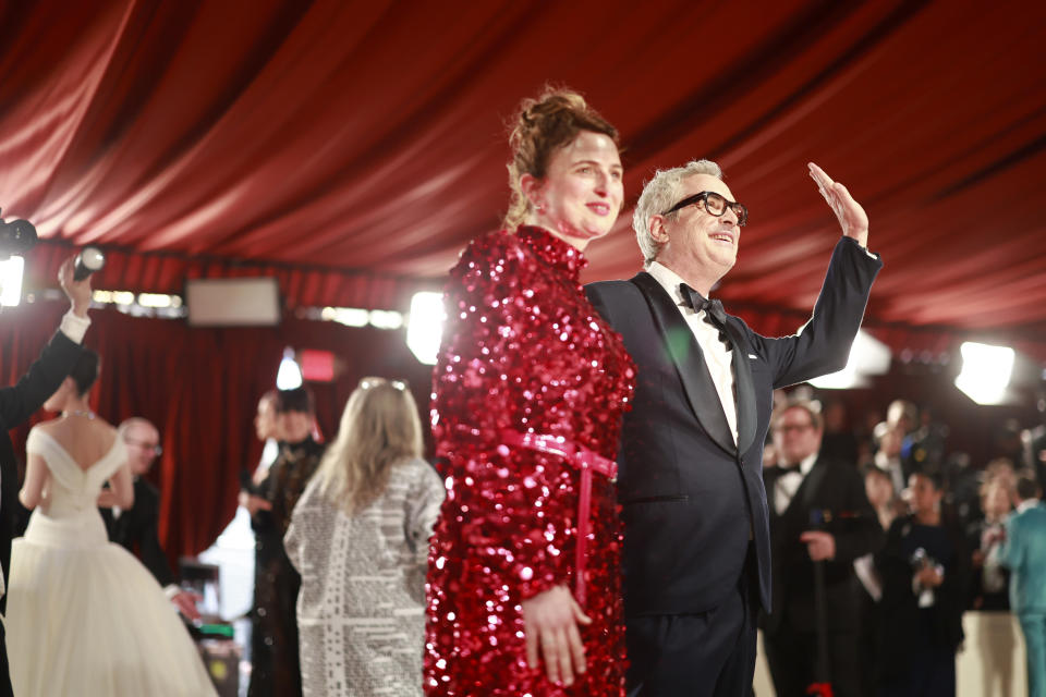 Alfonso waving to the crowd as he stands next to a guest