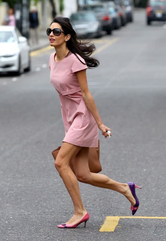 Amal Alamuddin court dans une robe rose et des escarpins assortis.