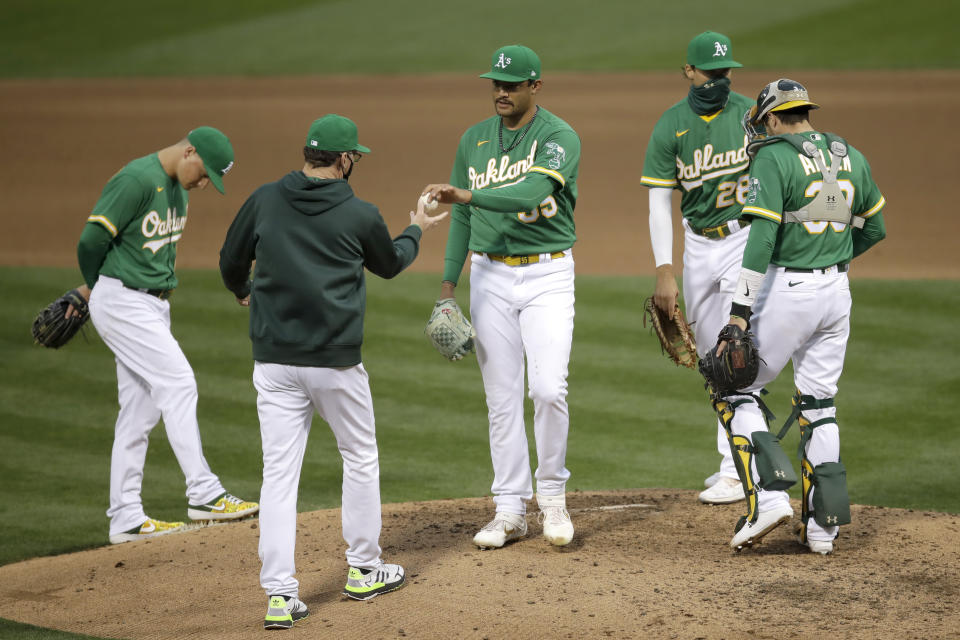 Oakland Athletics pitcher Sean Manaea, center, hands the ball to manager Bob Melvin as he is removed in the fourth inning of a baseball game against the Texas Rangers Wednesday, Aug. 5, 2020, in Oakland, Calif. (AP Photo/Ben Margot)