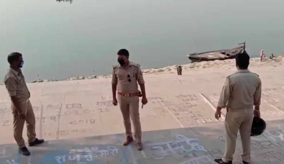 <p>Frame grab from video provided by KK Productions shows police officials stand at the banks of the river where several bodies were found in Ghazipur district in Uttar Pradesh on 11 May, 2021.</p> (AP)