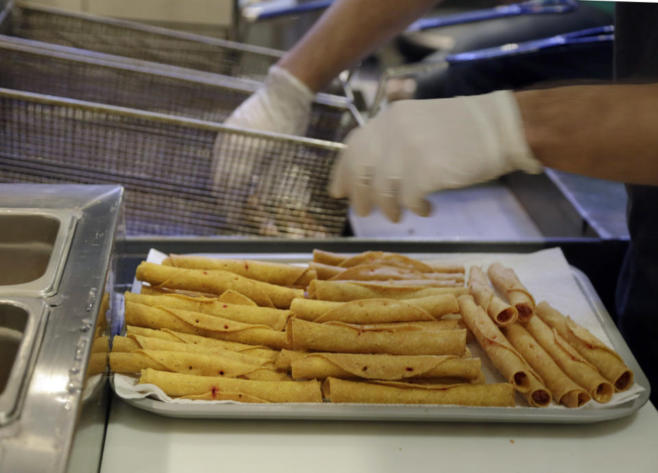 Buffalo chicken taquitos are removed from a fryer at Taquitoria, on New York's Lower East Side,Tuesday, Jan. 14, 2014. Taquitoria, a shop that serves only the deep-fried, cigar-like tortillas called taquitos, offers 40-piece boxes of the Buffalo chicken taquitos throughout football season. On Super Bowl game day they expect to do 99 percent of their business for takeout. (AP Photo/Richard Drew)